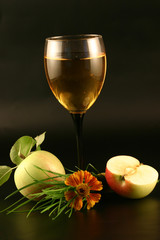 Glass of wine, apple and grass on a black background.