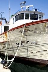 old fishing boat moored in harbour with peeling paint