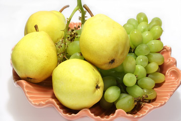 pears and grapes in pink vase with white background