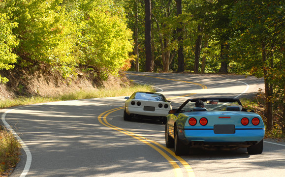 Two sports cars driving on a winding road