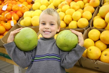 Fototapeta na wymiar boy with pamelo fruits in the shop