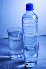 Bottle and glasses of mineral water with droplets