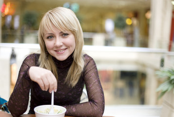 Eating blond girl with spoon in restaurant