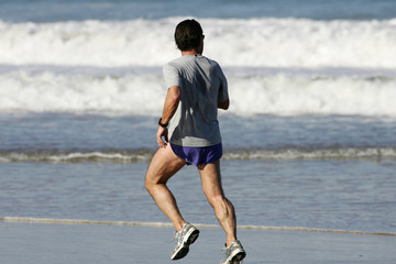 homme qui court sur la plage en regardant les vagues
