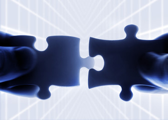 hands trying to fit two puzzle pieces together