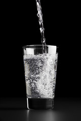 Pouring a glass of water against a black background