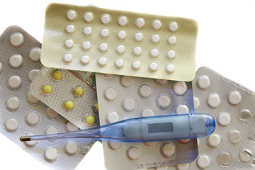pills and thermometer over white