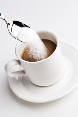 Spoon pouring sugar into a cup of coffee 