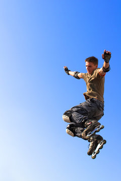 Roller boy jumping from parapet on the blue sky