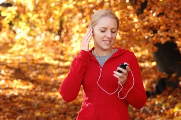 Young, sporty woman listening music in the park
