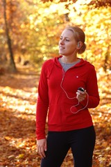 Young, sporty woman listening music in the park
