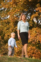 blue-eyed blond walks with the son in the park in autumn