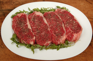platter of raw steaks with garnish