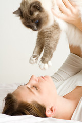 Lady playing with cat in bed