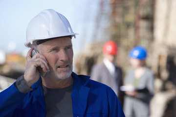 Oil rig survey engineers with one on cellphone