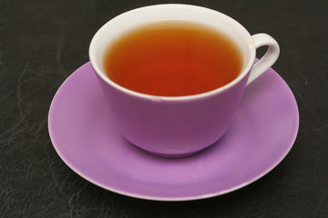 Lilac cup with tea on a black background