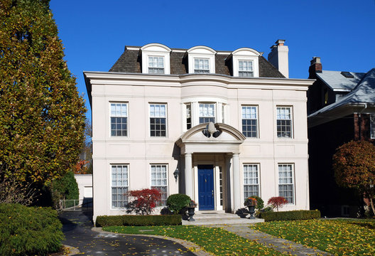large stucco house with dormers and blue door