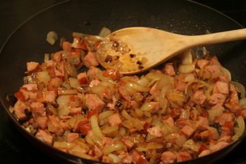 Pieces of onion and sausage being fried