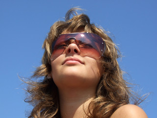 portrait of the girl in sunglasses on a background of the blue s