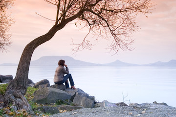 A young woman / lady is sitting and have a relax under a tree