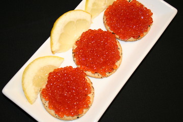 Red Russian caviar on biscuits, lemon beside
