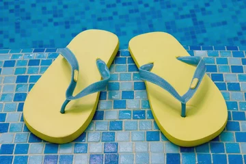 Fotobehang yellow sandals on the blue coast of pool © Georgiy Pashin