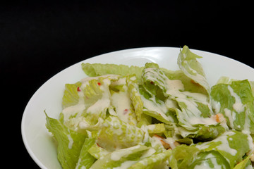 tossed salad in white bowl and black background