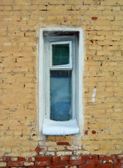 Fototapeta na wymiar Narrow window on a yellow brick wall