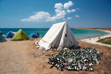 Camping on sea coast. Tent and bottles garbage. 