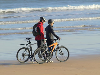 Fototapeta na wymiar Pareja con bicicletas paseando por la playa