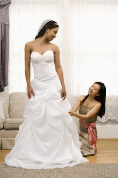 Bridesmaid adjusting bride's dress.