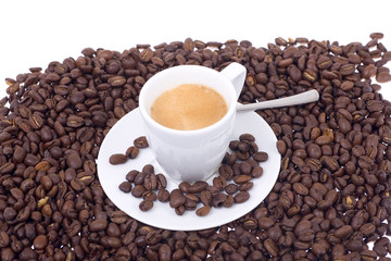 Espressotasse mit Löffel in Kaffeebohnenmeer