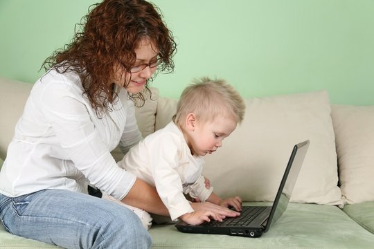 Young mother play with his son on notebook