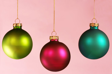Three colorful ornaments on light pink background.