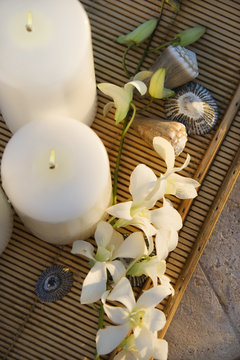 Above view of lit candles on tray with white orchid flowers.