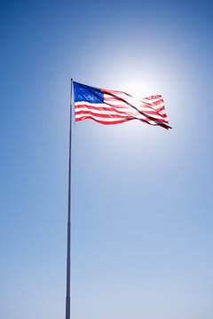American flag blowing in clear blue sky.