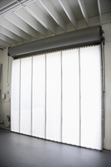 Interior of warehouse building with window and vertical blinds.