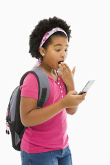 Girl with backpack looking at phone with surprised expression.