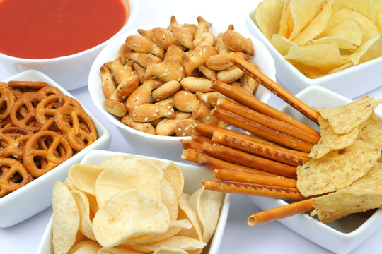 Pretzels, salty sticks, fish crackers and chips with salasa dip