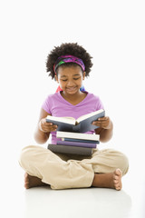 African American girl with large stack of books reading.