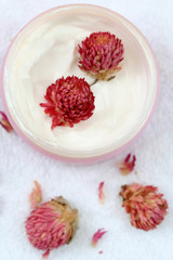 Spa essentials (cream, white towel and pink flowers)