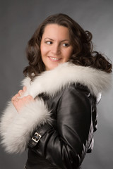 young woman in fur coat on gray background
