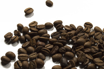 Dark coffee beans scattered on a white table