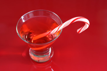 A christmas martini with a candy cane on a red background