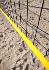 yellow volleyball net shot from above, visible sand