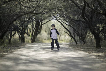 Young boy with a knit cap stopped on a tree-lined path