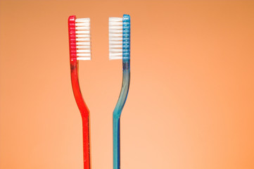 A set of his and hers toothbrushes in a glass container.