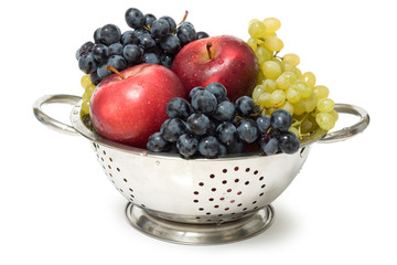 Colander with fruits on white background