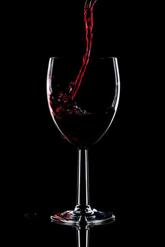 Red Wine Being Poured Into A Glass Splashing Over The Side. 