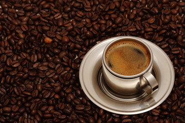 Chrome metal cup of coffee on the coffee beans.